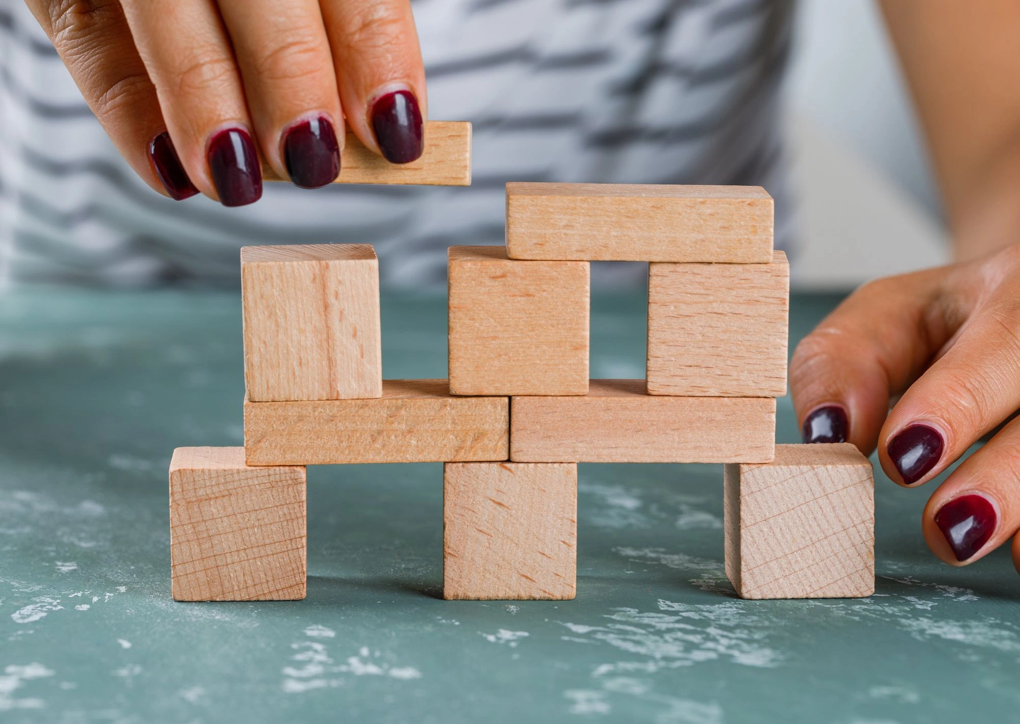 business concept side view woman building up tower from wooden blocks